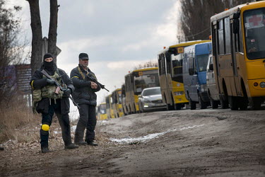 Members of the Territorial Defence force on duty at the roadside as a humanitarian convey of coaches drive westward, to try and evacuate civilians from towns west of Kyiv.