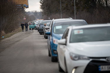 A long line of civilian cars, all heading eastward toward Kyiv. People trying to make their way into the capital are facing roadblocks and long queues of vehicles as well as the danger of shelling. Th...