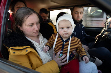 A woman holds a baby on her lap as a car full of people arrive in Kiev after fleeing from further east.  White flags and handwritten signs that read: 'children', are displayed on many of the vehicles...