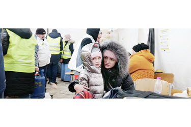 A mother and daughter, Ukrainian refugees, in a tent where volunteers are giving out hot drinks and food to people immediately after crossing the border.