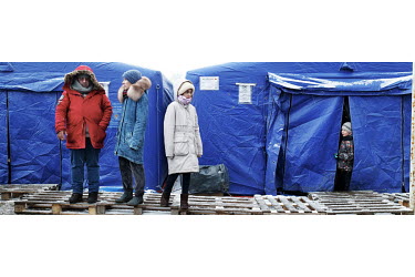A Ukrainian refugee family stand outside tents at the border used for shelter.