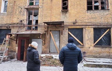 Local residents look at apartments damaged as the result of a 6am by Russian air strike on a nearby shoe factory. The pressure wave from the missiles shattered windows in surrounding buildings.
