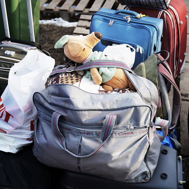 A teddy bear on top of luggage left outside of a tent where refugees family are hosted before leaving for other european cities.