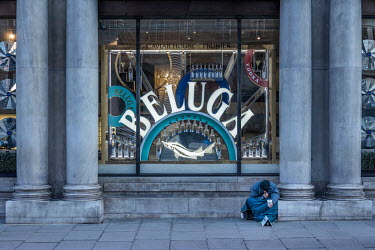 A homeless man begging for money sits outside in front of a window displaying Beluga caviar at The Cavier House shop in central London.