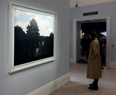 A woman looking at Rene Magritte's L'empire des lumieres, among the art on display at Sotheby's auctioneers.