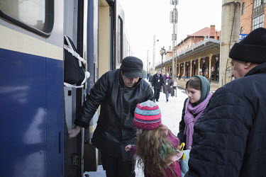 A man helping Ukrainian refugee children to board a train direct to Cluj Napoca.