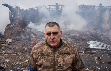 Army press officer Ermolenko stands in front of a smolderling shoe factory near Metalurhiv metro station which was hit at 6am by Russian air strikes. The pressure wave from the explosions shattered wi...