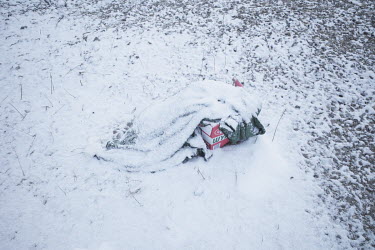 An abandoned sleeping bag covered by snow in a field at the Siret border crossing.