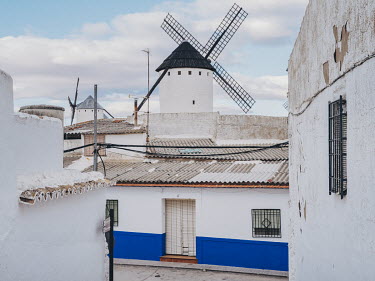 Historic windmills tower over a residential street in the old town of Campo de Criptana, the birthplace of writer Ana Iris Simon. The whitewashed structures are part of the visual iconography of the C...