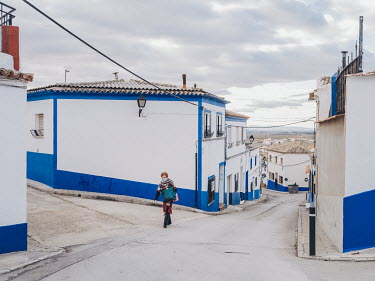 A woman walks up a quiet street in the old town of Campo de Criptana, a neighbourhood known locally as the Albaicin, referring to the ancient barrio of the same name in Granada. Many of the residences...