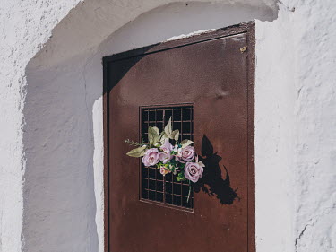 Synthetic plastic flowers on the door of a crypt at the Ermita de la Virgen de Criptana, a church on the outskirts of Campo de Criptana.