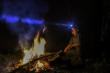 Bijesh T K, 38, surveys the forest with a headtorch during a night duty as a forest watcher. He has survived a tiger attack, sustaining injuries on his hand.