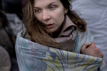Anastasia Azbukina, who has left her husband in Kharkiv where the fighting is raging, wraps a blanket tightly around herself as she stands outside at the Krakovetz border crossing. Together with her t...