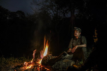 Bijesh T K, 38, sits by a burning fire during a night duty as a forest watcher in the forest of Waynand in Kerala. He has survived a tiger attack, sustaining injuries on his hand.