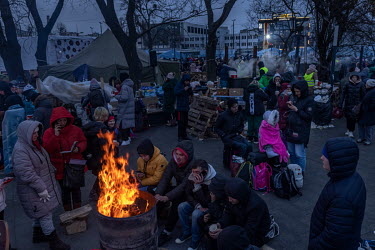 People gather around a fire burning in an oil drum outside the train station at Lviv, the main hub for people trying to escape the war in Ukraine. Most of the refugees here are heading to Poland arriv...