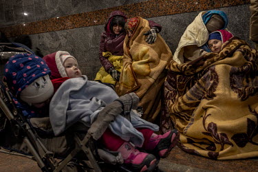A baby sits in its buggy, while Polina (5, right) huddles under a blanket with her mother, Anastasia Pichakhchi. The family fled Kharkiv after shelling hit their apartment bloc. Beside them Oksana (56...