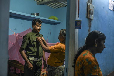 Bijesh TK's mother assists with buttoning up his uniform at his home in Wayanad. Bijesh is a temporary night watcher with the forest department and sustained serious permanent injury to his hand durin...