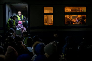 Railway staff help a woman and a child onto a train which is heading to Poland. Huge numbers of people, mainly women and children, have gathered at the train station in Lviv, the main hub for people t...