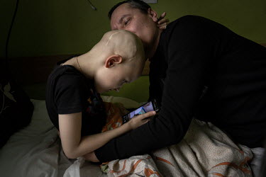 Leonid (8), who has scars on his head from the operations he has undergone, would rather play with a smart phone than receive kisses from his father, Andriy Ospov, who is openly worried and emotional....