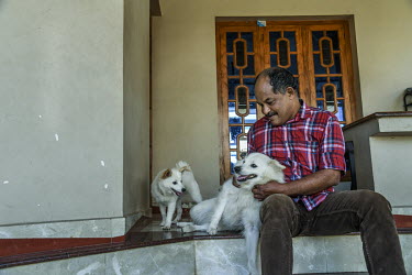 Sashikumar T with two small dogs at his home. He has survived two tiger attacks, in 2019 and 2021.