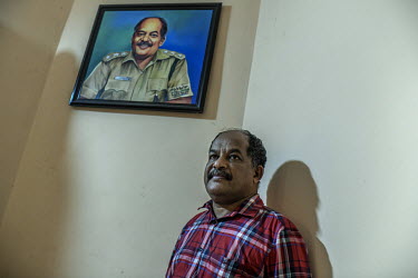 Sashikumar T next to a portriats of himself at his home. He has survived two tiger attacks, in 2019 and 2021.