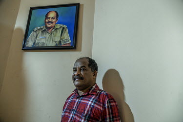 Sashikumar T next to a portriats of himself at his home. He has survived two tiger attacks, in 2019 and 2021.
