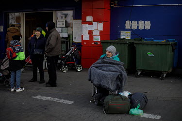 An elderly Ukrainian refugee woman sits in a wheelchair, wrapped in a blanket against the cold, outside an old Tesco supermarket building which has been converted into a humanitarian aid centre. It is...