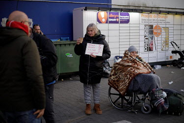 A woman holds a sign indicating where she is trying to get to as Ukrainian refugees gather outside an old Tesco supermarket building, which has been converted into a humanitarian aid centre, to board...