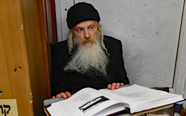 A Hasidic man prays and studies in a synagogue.