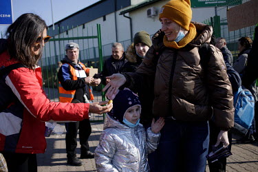 Child is offered a sweet by a volunteer after Ukrainian refugees pass the immigration post and cross into Poland.