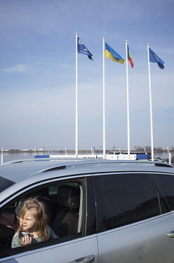 A young girl waits for her parents in the car while crossing the border into Romania.