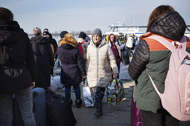 An elderly lady walks off the barge that brings refugees on foot from Ukraine across the Danube River to Romania.