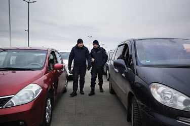 Two officials from the Romanian police walking between cars from Ukraine in the queue for passport control.