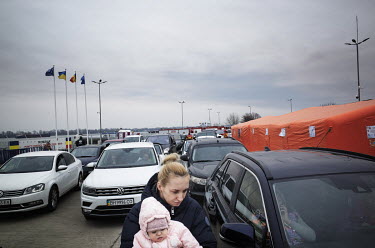 A mother and her child walking between cars from Ukraine in the queue for passport control.