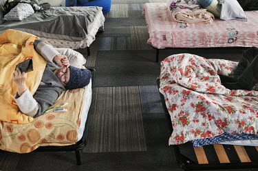 Nely, 57, reads messages on her phone while lying in a bed in a temporary shelter in Romania. She left Ukraine with her husband Ivan, 61, they are going to Spain to stay with their son.