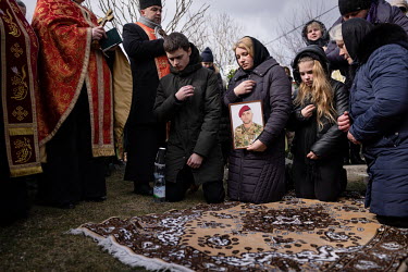 Oksana Ruschyshyn and two of her three children kneel in honour of their dead husband and father Roman Ruschyshyn (44). The funeral of the former police officer took place in Soposhyn, where they live...