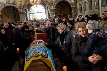 Oksana Ruschyshyn and her youngest son, named after his father Roman, mourn beside his coffin in the church where they, and hundreds of local villagers, have gathered for the funeral of Roman Ruschysh...