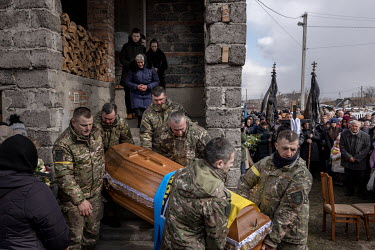 Comrades of Roman Ruschyshyn (44) carry his coffin out of his home as he begins his last journey through his hometown. The funeral of the former police officer took place in his home town of Soposhyn...
