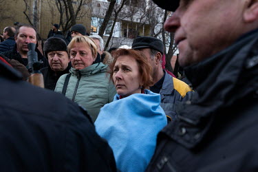 People among a crowd of concerned onlookers talk with police and Territorial Defence forces at a high rise civilian, residential estate in the Sviatoshynskyi district of Kiev that was targeted by Russ...