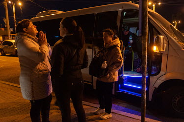 A woman offers a prayer after a group of evacuees from Chernigiv arrive by mini bus at the Central Railway station.