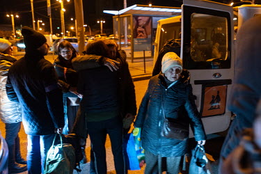 People hug after a group of evacuees from Chernigiv arrive by mini bus at the Central Railway station.