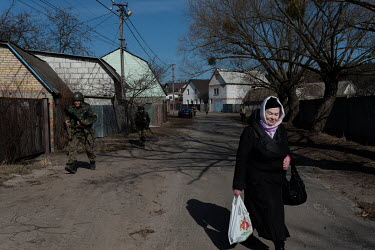 Members of the Ukrainian Military Organisation pass a woman carrying a shopping bag while they are on a training exercise. The UMO was created over 100 years ago to protect Ukrainan independence and f...