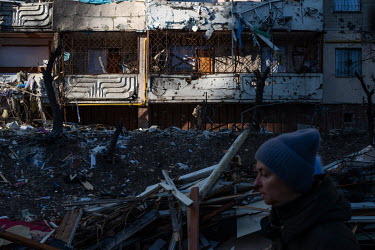 People pass the debris piled up outside a badly damaged residential apartment block, one of several civilian, residential areas of western Kiev that were targeted by Russian shelling over several days...