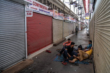 Migrant workers rest outside a closed shop selling non-essential products during the weekend lockdown on 11 April 2021.