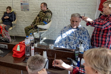 A soldier waits to have a haircut in a hairdresser's shop.