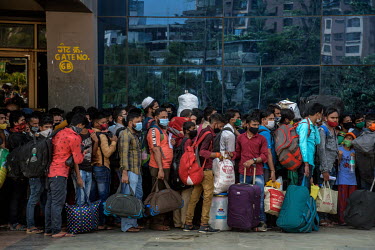Migrant workers queue outside the Lokmanya Tilak Terminus (LTT) station to get to a train departing to their home towns after it became clear that the local government was considering a complete lockd...