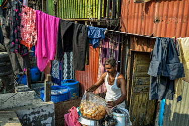 Rakesh Kumar Yadav arranges his snacks which he sells on the roadside outside his house in the slums of Mumbai. He says he is planning to stay in Mumbai if there is no lockdown and if its announced th...