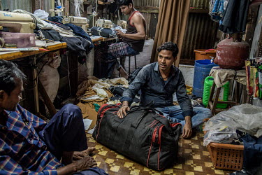 Karim Ansari (right) who works in a local footwear factory packs his bag at his friend's shop as he planning to leave that night by train from Mumbai to his hometown. The factory owner where he works...