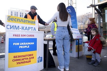 Ukrainian refugees receive free sim cards from an O2 stall at an arrivals centre in the Hauptbahnhof, the train station where Ukrainian refugees disembark trains From Poland.