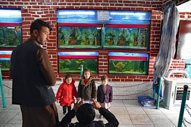 A man with his children looking at aquariums in Kabul Zoo.